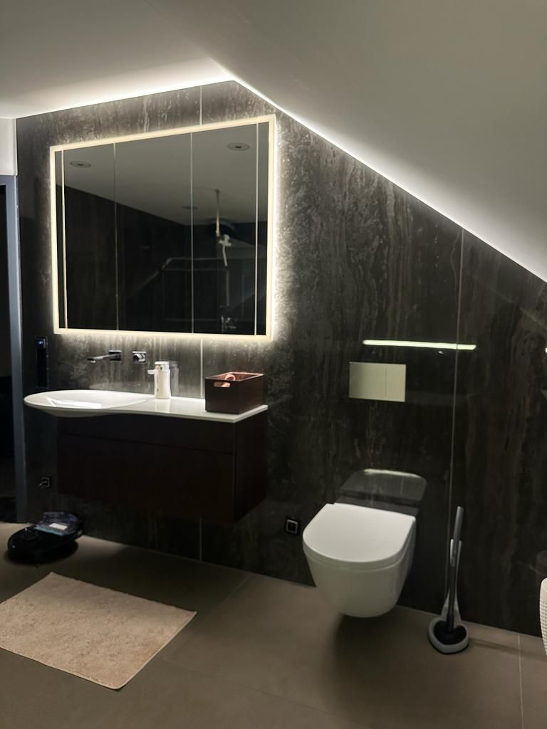 Neu gestaltetes Badezimmer, mit indirekter Ambientebeleuchtung des Spiegels über dem Waschbecken.