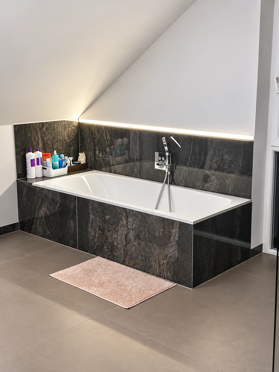 Eingeflieste Badewanne unter einer Dachschräge mit indirekter Beleuchtung